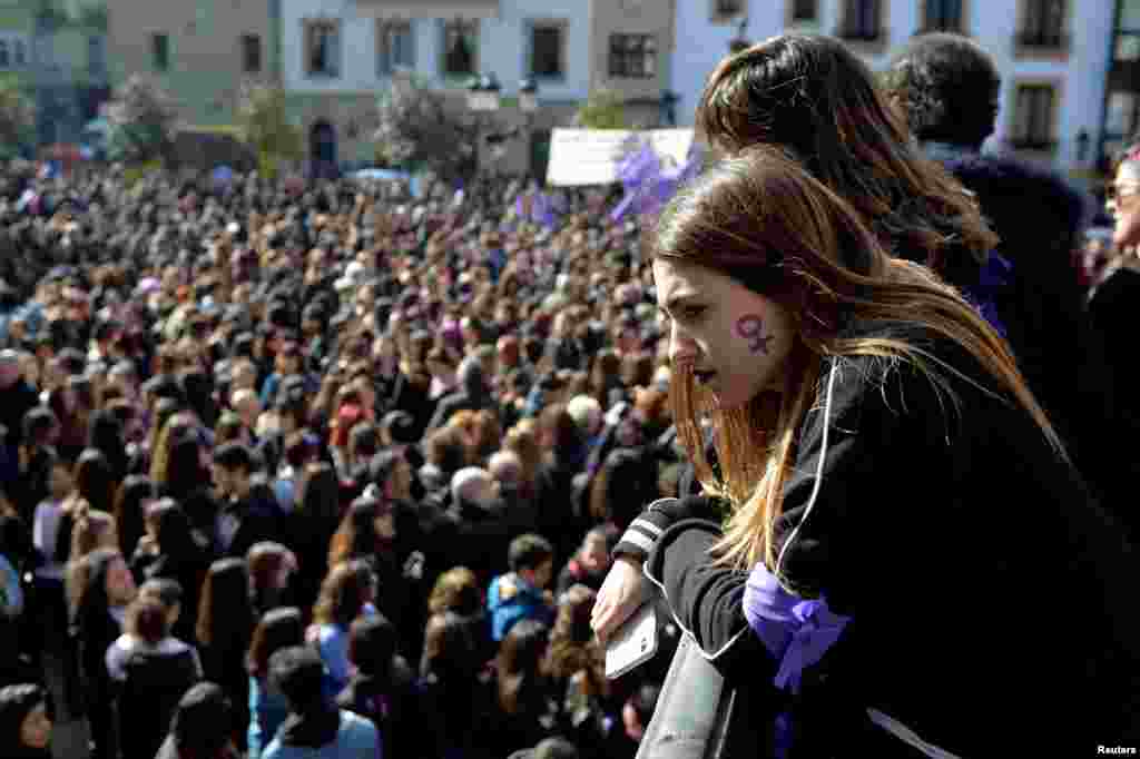 A woman with a female gender symbol on her cheek observes a demonstration for women's rights in Bilbao, Spain, March 8, 2018, on International Women's Day. 