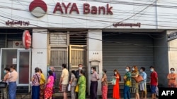 People wait for a branch of the AYA Bank to open, ahead of a long holiday stretch for the Myanmar New Year, also known as Thingyan, in Yangon on April 12, 2021, as the country remains in turmoil after the February military coup. (Photo by STR / AFP)