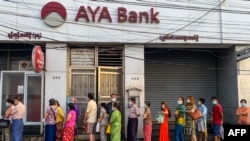 People wait for a branch of the AYA Bank to open, ahead of a long holiday stretch for the Myanmar New Year, also known as Thingyan, in Yangon on April 12, 2021, as the country remains in turmoil after the February military coup. (Photo by STR / AFP)