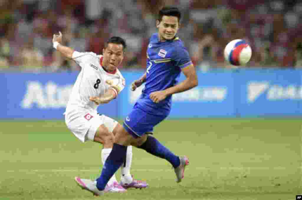 Nay Lin Tun of Myanmar, left, chips the ball past Peerapat Notechaiya of Thailand during the soccer final at the SEA Games in Singapore, Monday, June 15, 2015. (AP Photo/Joseph Nair)