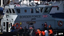 UK Border Force officials transfer migrants intercepted whilst travelling in a RIB from France to Dover from a Patrol Vessel to the Border Force cutter HMC Speedwell and the tug boat DHB Dauntless at the Marina in Dover, southeast England on August 13, 20