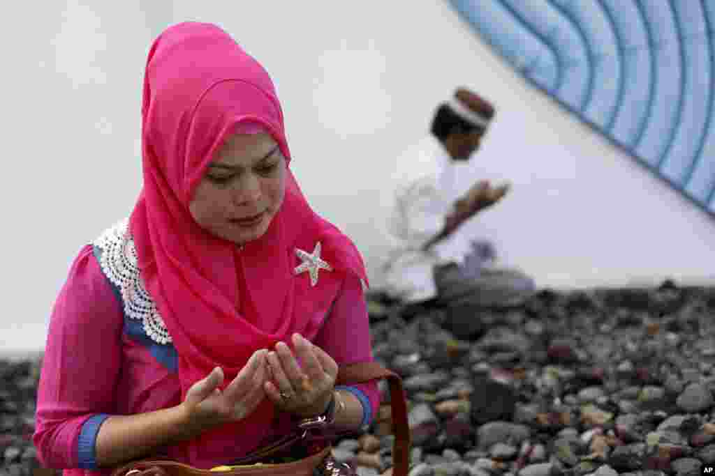 A woman mourns victims of the December 2004 Asian tsunami, praying at a mass grave in Siron, Aceh Besar, Indonesia, Dec. 26, 2014. 