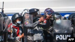 A police officer (C) aims a gun during clashes with protesters taking part in a demonstration against the military coup in Naypyidaw on February 9, 2021. (Photo by STR / AFP)