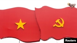 A worker erects decoration with images of the Vietnamese national flag (L) and communist flag before the upcoming 12th national congress of the ruling Communist Party of Vietnam (CPV) on a street in Hanoi January 4, 2016.