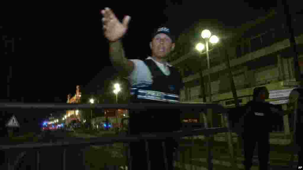 In this video grab taken Thursday July 14, 2016, a policeman chase people out of the cordoned-off area after a truck drove on to the sidewalk and plowed through a crowd of revelers who’d gathered to watch the fireworks in the French resort city of Nice. 