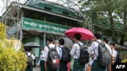 Students wait outside a school entrance in Sittwe, capital of western Rakhine State on June 1, 2021. - Schools in Myanmar opened on June 1 for the first time since the military seized power, but teachers and students are set to defy the junta's calls for 