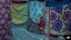 A young Rohingya refugee boy stands outside a tent at a refugee camp alongside the banks of the Yamuna River in the southeastern borders of New Delhi, sprawling Indian capital, July 1, 2021