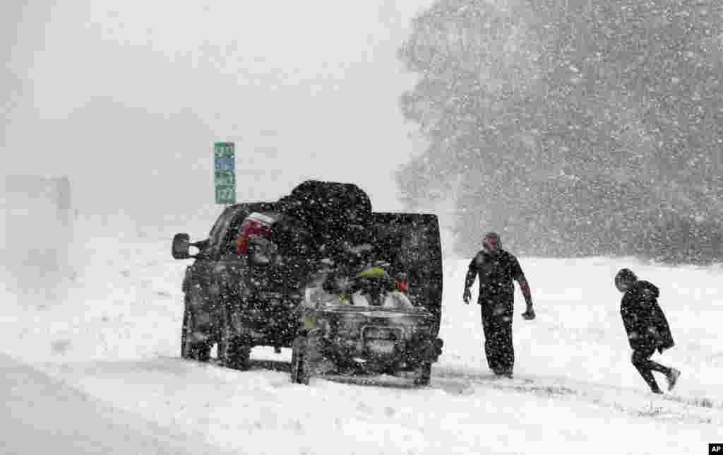 People attend to their vehicle on Interstate 26, near Savannah, Ga., Jan. 3, 2018. A brutal winter storm dumped snow in Tallahassee, Fla., Wednesday for the first time in nearly three decades before slogging up the Atlantic coast.