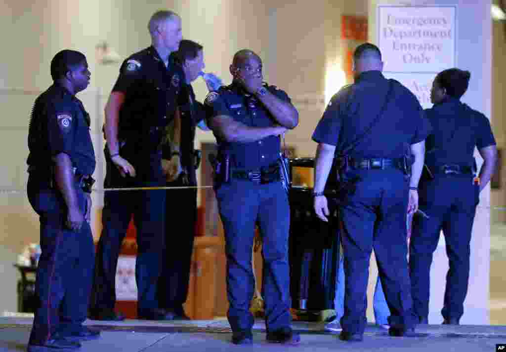 A Dallas police officer covers his face as he stands with others outside the emergency room at Baylor University Medical Center, July 8, 2016, in Dallas. 