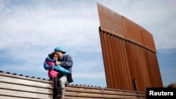 Migran Peyi Ondiras ki t ap vole sou yon kloti pou yo te ka kite Meksik epi antre Ozetazini, nan zòn Tijuana, Meksik (Foto: REUTERS/Mohammed Salem/Dat: 12 desanm 2018). 