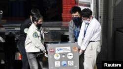 Japan Aerospace Exploration Agency's (JAXA) staff carry a case containing Hayabusa2's capsule with extensive samples of an asteroid as it arrives at JAXA Sagamihara Campus in Sagamihara in this photo taken by Kyodo, Dec. 8, 2020. 