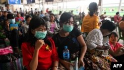 People wear face masks as a preventive measure against the COVID-19 coronavirus while waiting for a ride at the central railway station in Yangon on March 19, 2020. (Photo by Ye Aung THU / AFP)