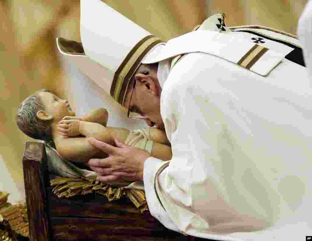 Pope Francis kisses a statue of Baby Jesus as he celebrates the Christmas Eve Mass in St. Peter&#39;s Basilica at the Vatican, Dec. 24, 2014.