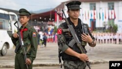 This photo taken on July 28, 2016 shows two Myanmar armed rebels from the Kachin Independence Army (KIA) securing the compound (behind) where Myanmar ethnic rebel leaders and representatives have gathered for a four-day summit in Mai Ja Yang, the KIA cont