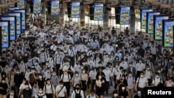 FILE PHOTO: Commuters wearing face masks arrive at Shinagawa Station at the start of the working day amid the coronavirus disease (COVID-19) outbreak, in Tokyo, Japan, August 2, 2021 .REUTERS/Kevin Coombs/File Photo