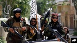 FILE - Taliban fighters display their flag on patrol in Kabul, Afghanistan, Aug. 19, 2021.