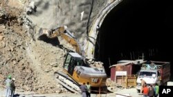 Rescuers work heavy machinery on Nov. 18, 2023, at the entrance to the site of an under-construction road tunnel that collapsed in mountainous