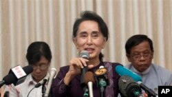 Myanmar opposition leader Aung San Suu Kyi, center, talks to journalists during a news conference at her residence, Saturday, July 11, 2015.