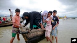 Bangladeshi villagers help two elderly Rohingya women from a boat after crossing a canal at Shah Porir Deep, in Teknak, Bangladesh, Aug. 31, 2017.