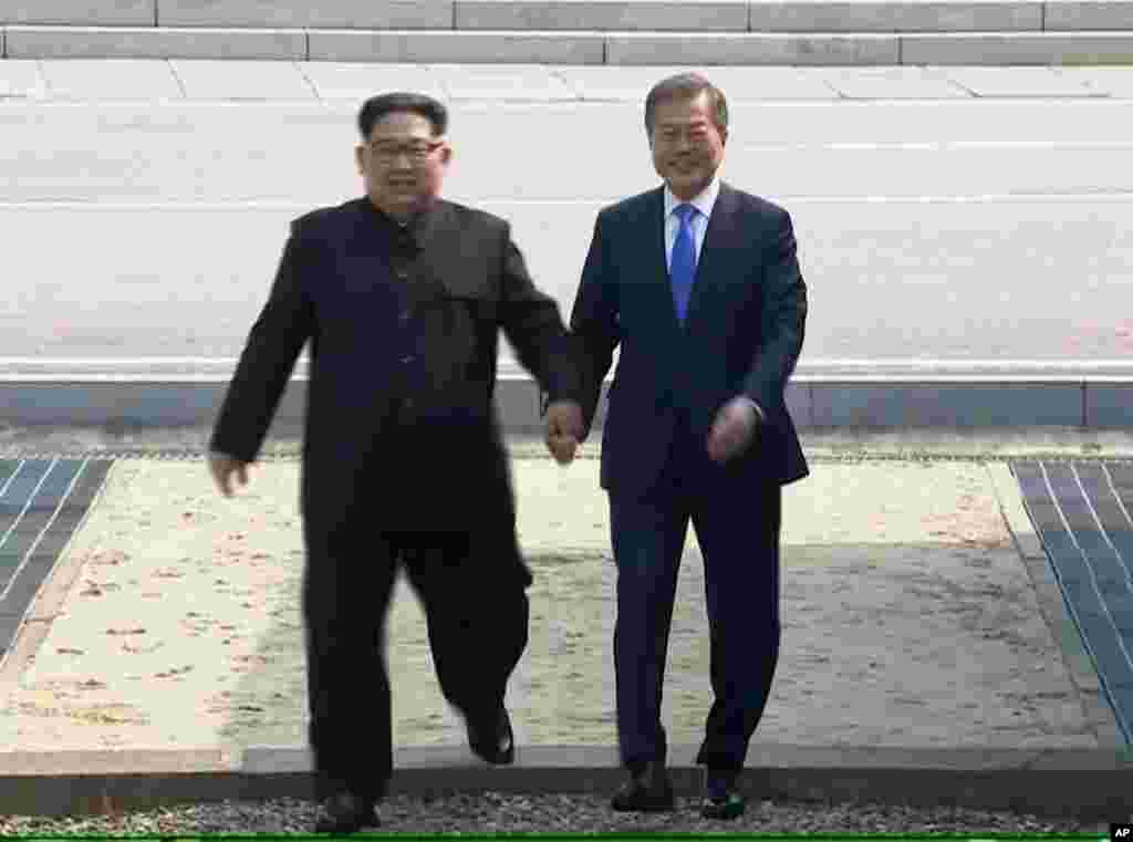 In this image taken from video provided by Korea Broadcasting System, April 27, 2018, North Korean leader Kim Jong Un, left, crosses the border into South Korea, along with South Korean President Moon Jae-in for their historic face-to-face talks, in Panmu