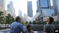 Visitors to the National September 11 Memorial take in the view from the north pool, Saturday, Sept. 10, 2016, in New York. Sunday marks the 15th anniversary of the attacks on the World Trade Center. (AP Photo/Mary Altaffer)