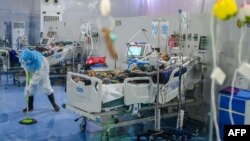 This photo taken on January 1, 2021 shows a doctor cleaning the floor of the intensive care unit (ICU) of the Ayeyarwady Covid Center at the Thuwana football stadium in Yangon, amid the ongoing Covid-19 coronavirus pandemic. (Photo by Ye Aung THU / AFP) /