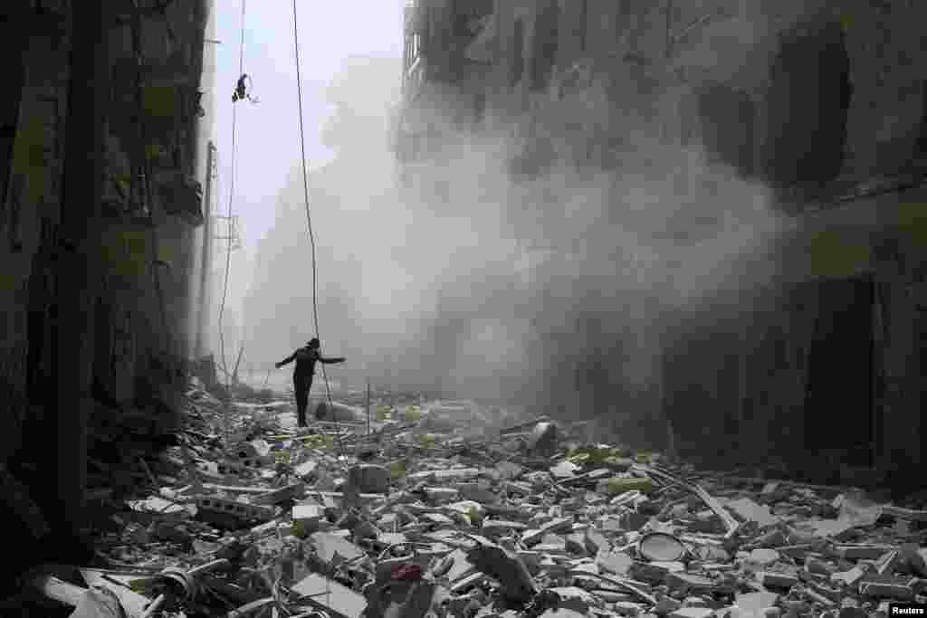 A man walks on the rubble of damaged buildings after an airstrike on the rebel held al-Qaterji neighbourhood of Aleppo, Syria, Sept. 25, 2016.