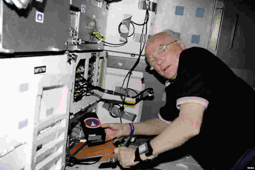 STS-95 payload specialist John Glenn works with the Osteporosis Experiment in Orbit (OSTEO) experiment located in a locker in the Discovery's middeck, Nov. 18, 1998.