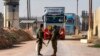 Israeli soldiers stand guard as trucks carrying humanitarian aid move at the Israeli side of the Kerem Shalom border crossing with the southern Gaza Strip on December 19, 2023, amid the ongoing conflict between Israel and the Palestinian militant group Ha