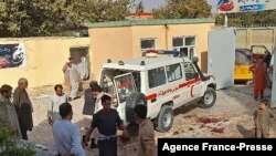 Afghan men stand next to an ambulance after a bomb attack at a mosque in Kunduz on Oct. 8, 2021.