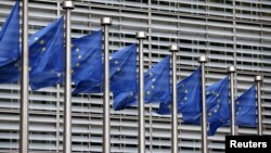 FILE - European Union flags flutter outside EU Commission headquarters in Brussels, Belgium, Oct. 28, 2015.