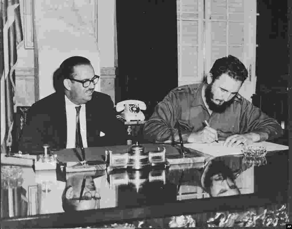 FILE - Cuban Prime Minister Fidel Castro signs decree nationalizing all American-owned banks in Cuba, Sept. 17, 1960.