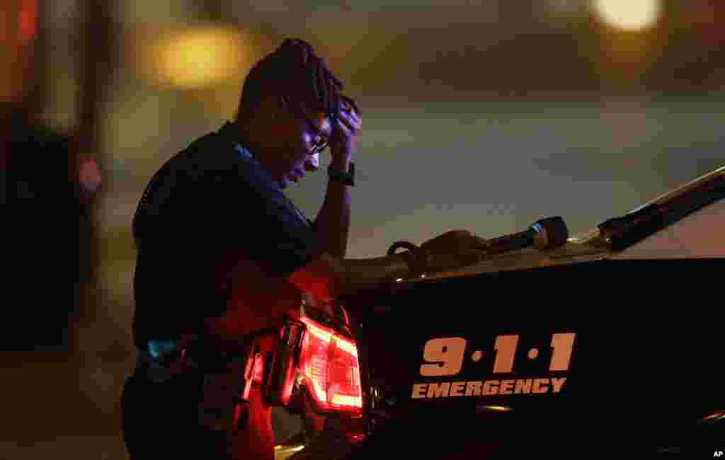 A Dallas police officer, who did not want to be identified, takes a moment as she guards an intersection in the early morning after a shooting in downtown Dallas on July 8, 2016.