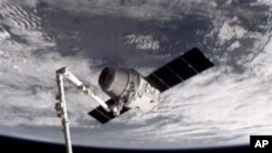 This image provided by NASA-TV shows the SpaceX Dragon commercial cargo craft, top, after Dragon was grappled by the Canadarm2 robotic arm and connected to the International Space Station, Friday, May 25, 2012. Dragon is scheduled to spend about a week do