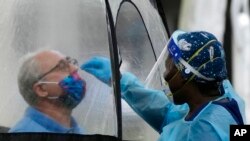 FILE - A man is tested for COVID-19 at a walk-up testing site run by Nomi Health, in downtown Miami, Dec. 28, 2021.