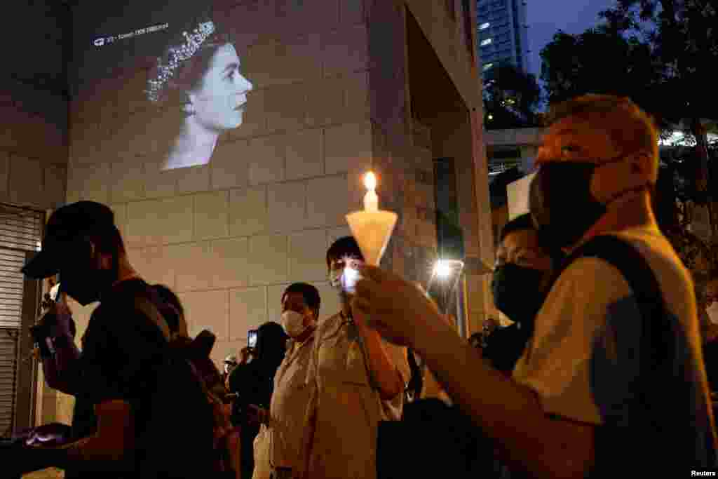 People hold candles during the funeral of Britain's Queen Elizabeth, outside the British Consulate-General, in Hong Kong