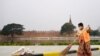 A cleaner wearing a face mask sweeps a road near the ramparts of the former royal palace