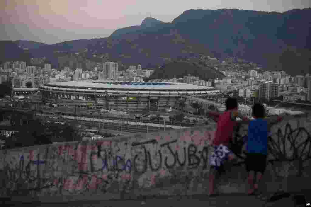 Two boys look out from the Mangueira slum toward the Maracana Stadium that is hosting the 2016 Summer Olympics opening ceremonies in Rio de Janeiro, Brazil, Aug. 5, 2016.