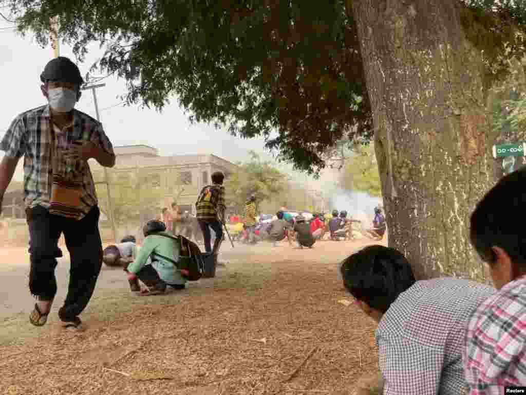 Protesters take cover during clashes with security forces in Monywa, Myanmar March 21, 2021,