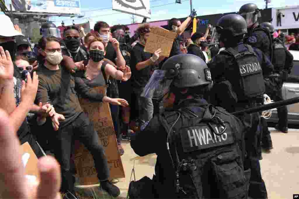 A Los Angeles police officer threatens protesters during a protest over the death of George Floyd Saturday, May 30, 2020, in Los Angeles. Protests across the country have escalated over the death of George Floyd who died after being restrained by Minneapo