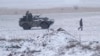 A Ukrainian soldier carries water past a vehicle standing on a field between the towns of Debaltseve and Artemivsk, eastern Ukraine, Feb. 16, 2015. 