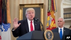 President Donald Trump, accompanied by Vice President Mike Pence, right, speaks during a signing ceremony for executive orders regarding trade in the Oval Office at the White House, March 31, 2017, in Washington. 