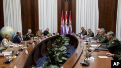 In this handout photo released by Russian Defense Ministry Press Service, British Defense Secretary Ben Wallace, second left, and Russian Defense Minister Sergei Shoigu, second right, talk to each other during their meeting in Moscow, Russia, Friday, Feb. 11, 2022.