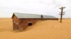 A worker rests on the roof of a building surrounded by sand as a result of desert encroachment at Ogrein Railway Station at the Red Sea State August 1, 2013. 