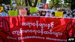 Doctors and health workers hold a banner and signs as they take part in a protest against the military coup in front of the Chinese embassy in Yangon on February 11, 2021. (Photo by Ye Aung THU / AFP)