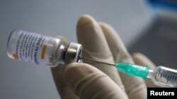 FILE PHOTO: A health worker holds a syringe and a vial of the Sinovac coronavirus disease (COVID-19) vaccine at a market in Bangkok, Thailand, March 17, 2021. REUTERS/Athit Perawongmetha/File Photo