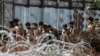 Migrants, who were found at sea on a boat, walk in a line of twos to board a truck to be taken to Mee Tike temporary refugee camp located near the Bangladesh border fence, at Kanyin Chaung jetty, outside Maungdaw township, northern Rakhine state, Myanmar June 4, 2015.