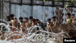 Migrants, who were found at sea on a boat, walk in a line of twos to board a truck to be taken to Mee Tike temporary refugee camp located near the Bangladesh border fence, at Kanyin Chaung jetty, outside Maungdaw township, northern Rakhine state, Myanmar June 4, 2015.