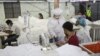 This photo taken on May 8, 2020 shows workers wearing face masks sewing disposable surgical gowns for health workers as protection from the COVID-19 coronavirus at a garment factory in Yangon. - The factory which has switched from making clothes for expor