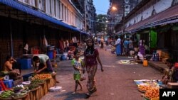 A woman walks with a boy through a street market in Yangon on April 2, 2021. (Photo by STR / AFP)